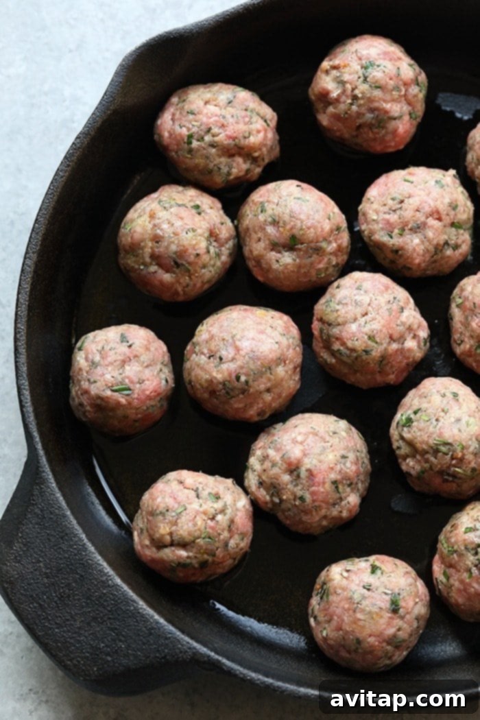 Raw meatballs neatly arranged in a cast iron pan, ready for cooking and glazing with balsamic vinegar.