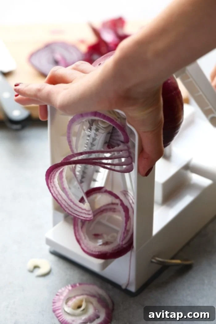 Oven Caramelized Onions 3 Close-up of thinly sliced red onions on a cutting board, ready for caramelization
