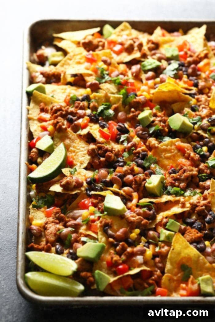 A large platter of loaded chicken nachos, overflowing with cheese and toppings.