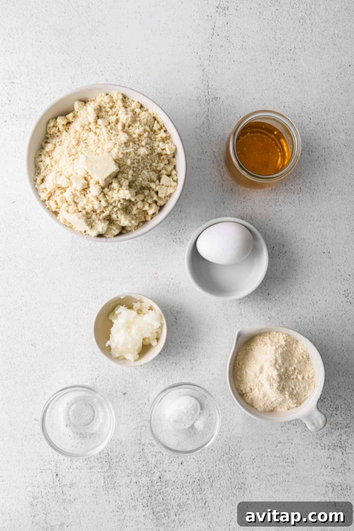 Essential ingredients for making grain-free almond flour sugar cookies laid out on a kitchen countertop.