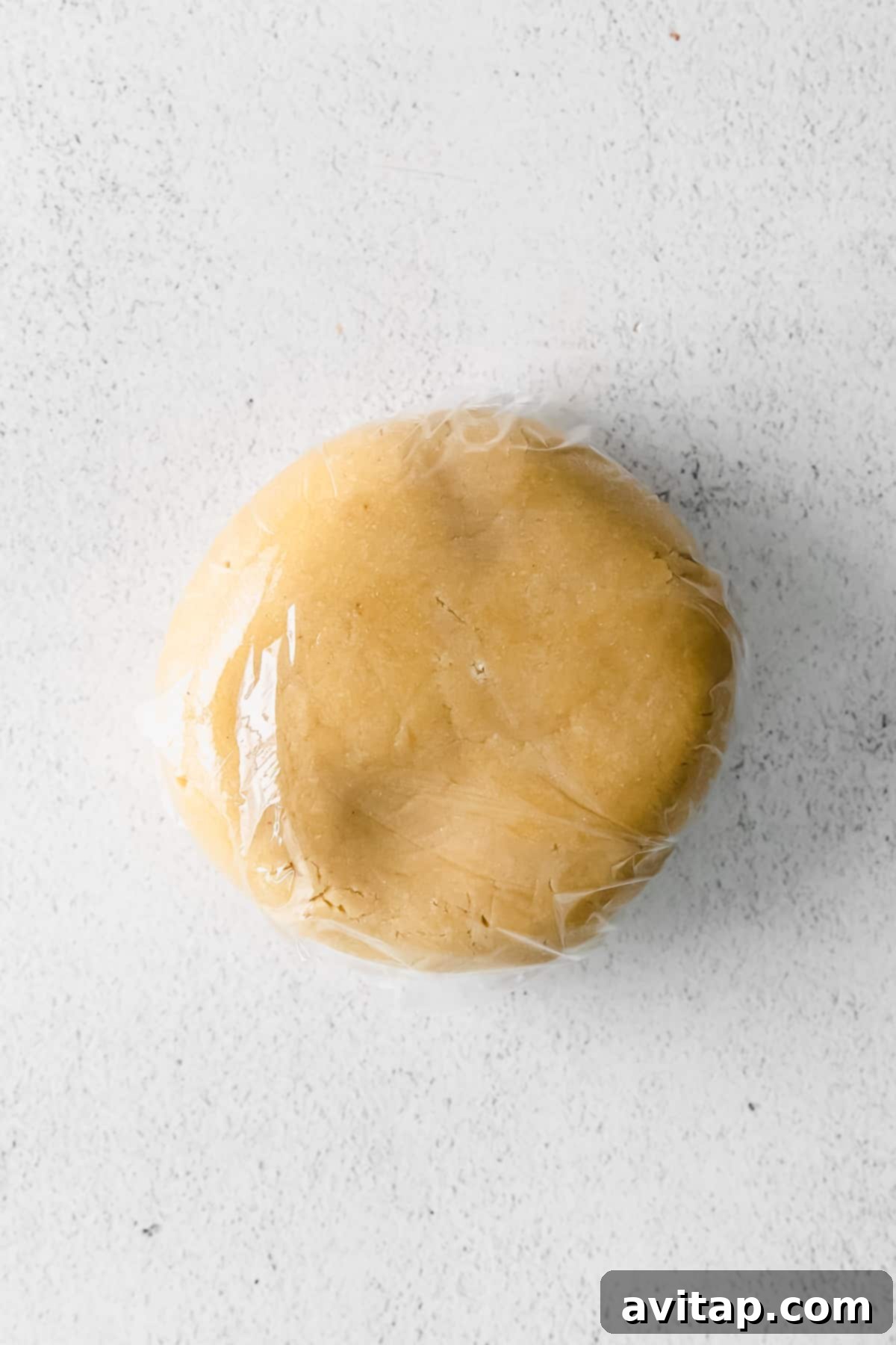 Almond flour cookie dough neatly wrapped in plastic wrap, chilling in the refrigerator.