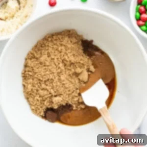 A person mixing ingredients in a bowl to form cookie dough.