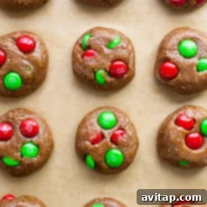 M & m cookies shaped on a baking sheet, ready for the oven, with red and green M&Ms.