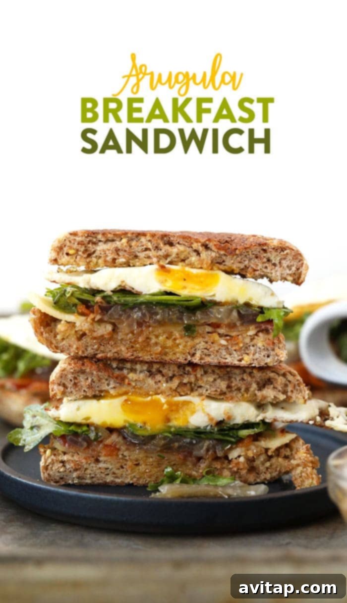 A vibrant Arugula Breakfast Sandwich with Caramelized Onions, featuring a golden fried egg, crispy bacon, and fresh greens on a toasted English muffin, ready for a healthy morning.