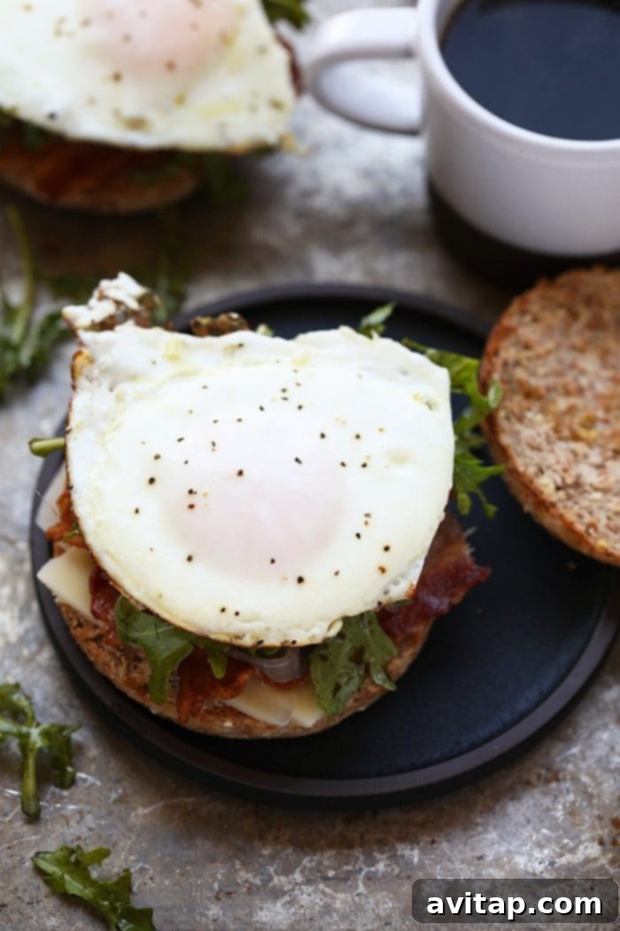 The finished Arugula Breakfast Sandwich with Caramelized Onions, showing its rich layers and golden toasted muffin, ready to be enjoyed.