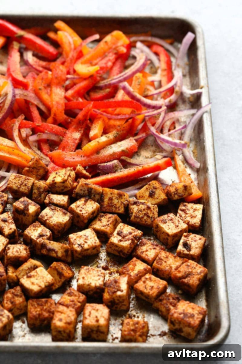 An overhead shot showcasing the various fresh ingredients for the Meal Prep Sheet Pan Tofu Quinoa Burrito Bowls, including pressed tofu, sliced peppers, onions, and cooked quinoa, ready for assembly and cooking.