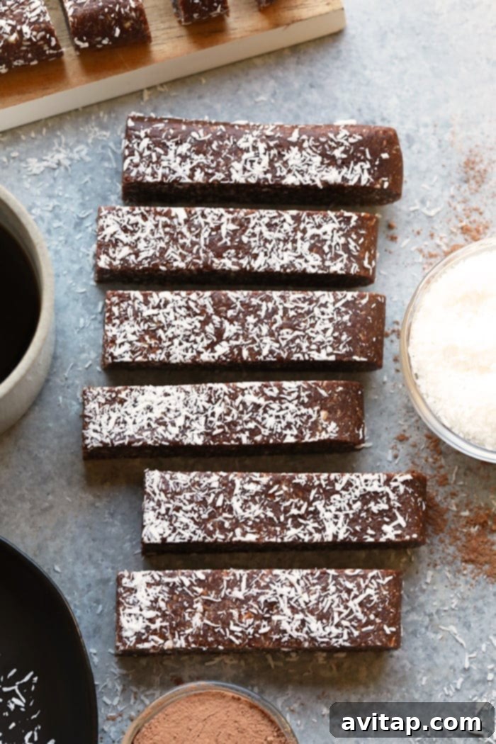 A hand reaching for a No-Bake Chocolate Coconut Date Bar, emphasizing its appeal as a convenient, grab-and-go healthy snack.