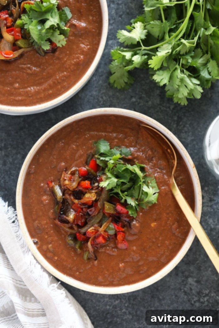 Hearty Slow Cooker Black Bean Soup in a Bowl A steaming bowl of delicious crock pot black bean soup, garnished with fresh cilantro and a dollop of sour cream or Greek yogurt, ready to be enjoyed.