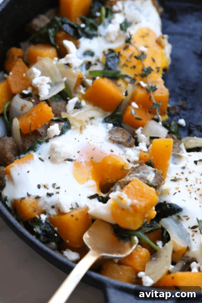 Butternut squash and other hash ingredients simmering in a cast iron skillet before eggs are added.