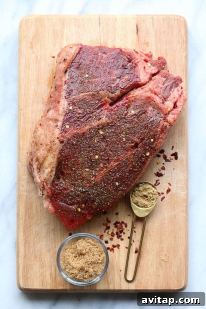 A raw boneless beef chuck roast on a wooden cutting board, ready for seasoning and cooking.