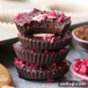 a stack of chocolate almond butter cups topped with raspberries and nuts.