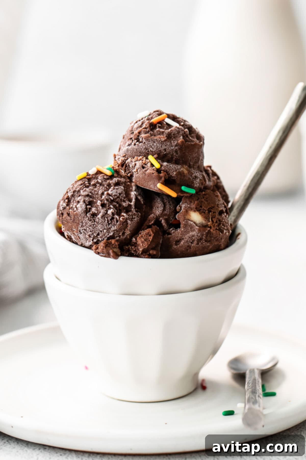 Guilt-Free Chocolate Protein Bliss 2 Decadent chocolate protein ice cream in a white bowl, generously topped with colorful sprinkles, ready to be enjoyed.