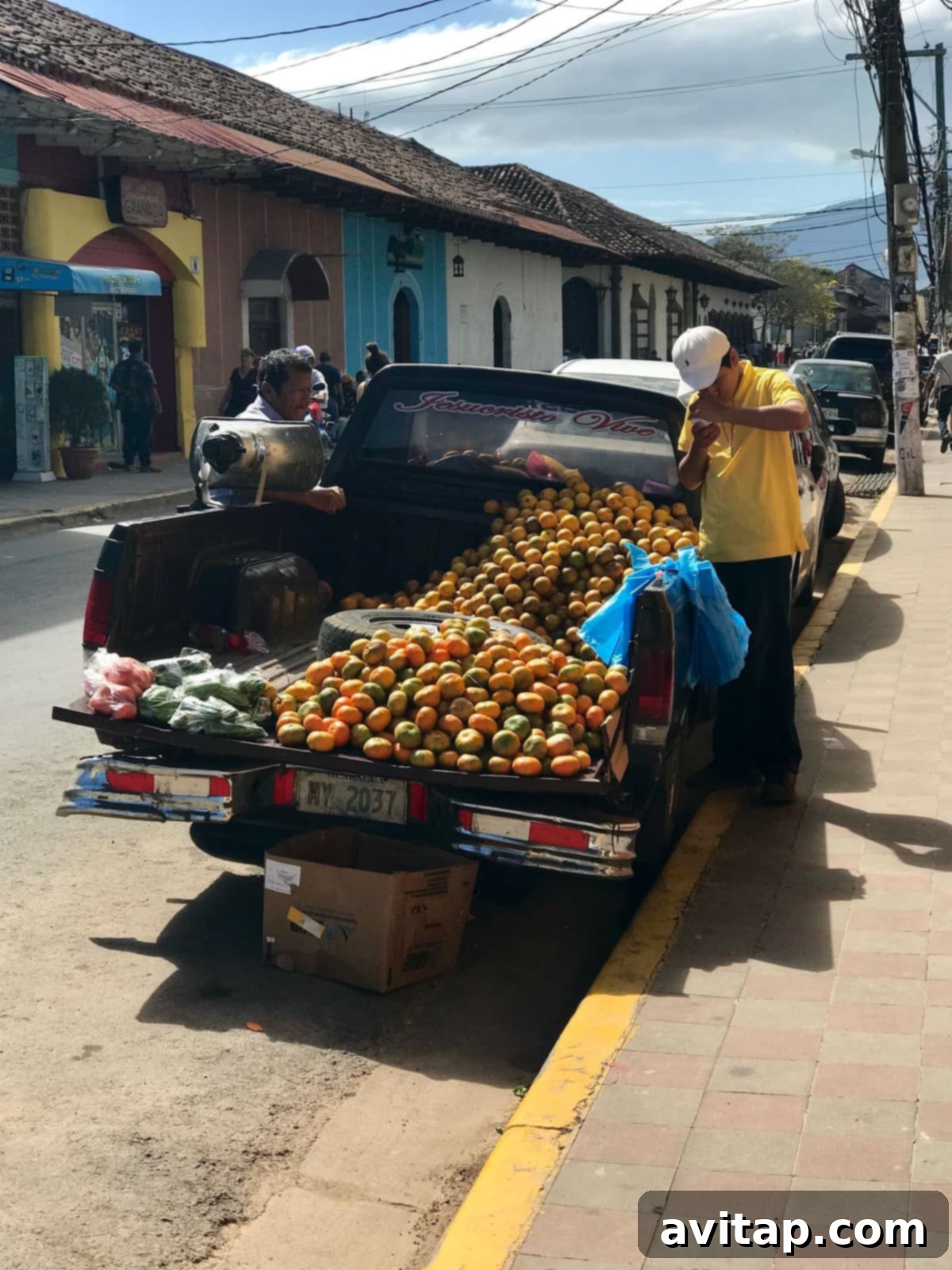 A colorful truck filled with oranges, parked on a vibrant street in Granada, Nicaragua.
