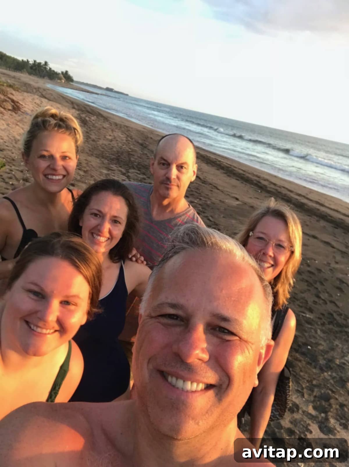 Three friends smiling and taking a selfie on a picturesque beach in Nicaragua, perfect for a yoga retreat.
