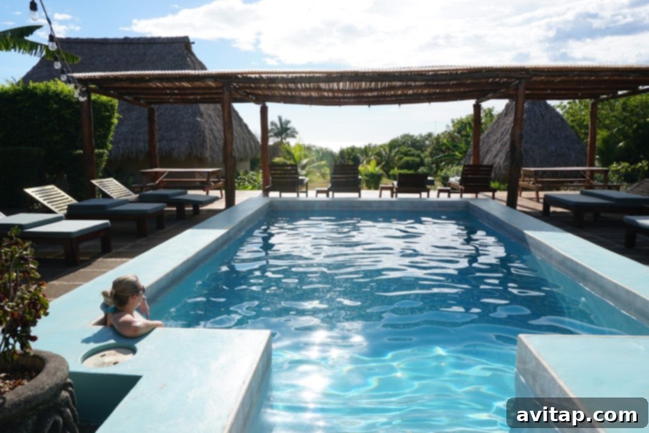 A stunning view of the swimming pool and patio area at Coco Loco Eco-Resort in Nicaragua, surrounded by lush greenery.