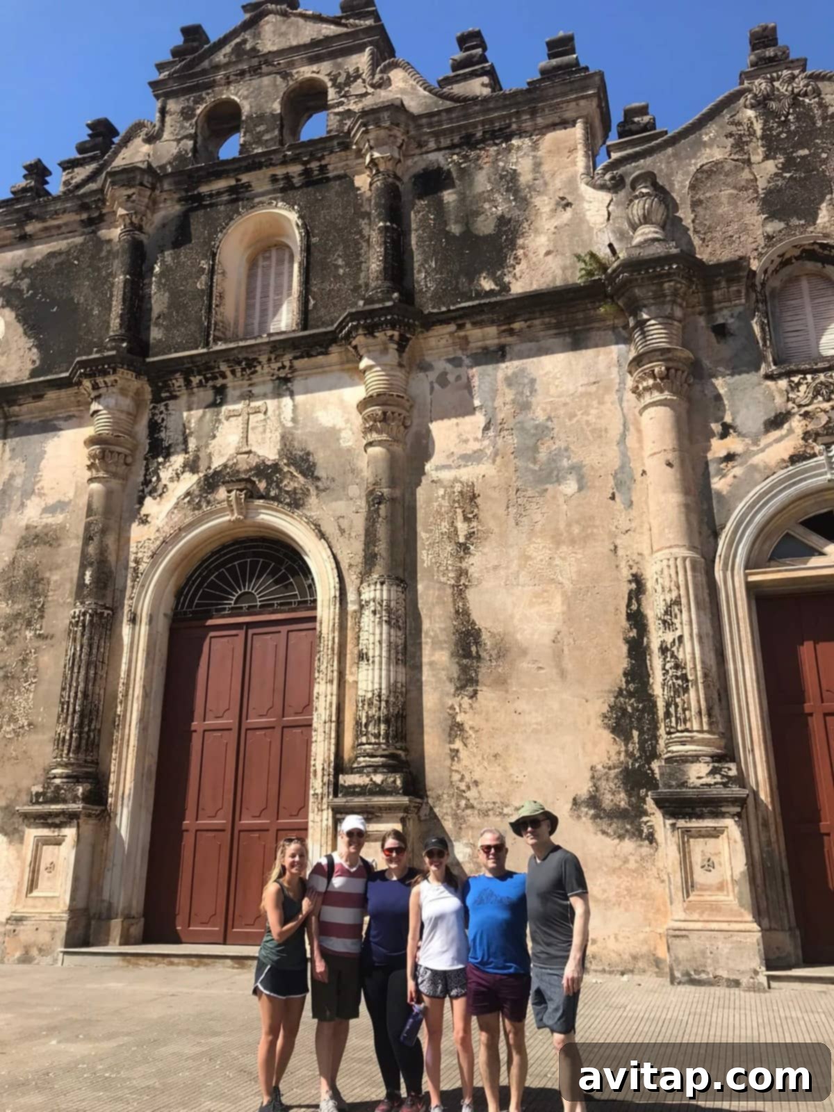 A group of people standing in front of a historic yellow church in Granada, Nicaragua, enjoying a city tour.