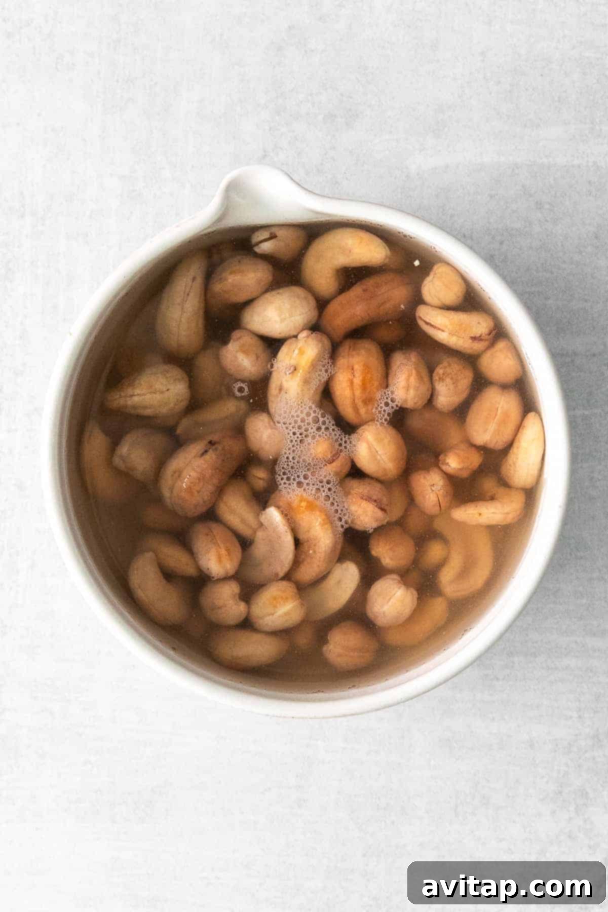 raw cashews soaking in water, preparing for a creamy vegan sauce
