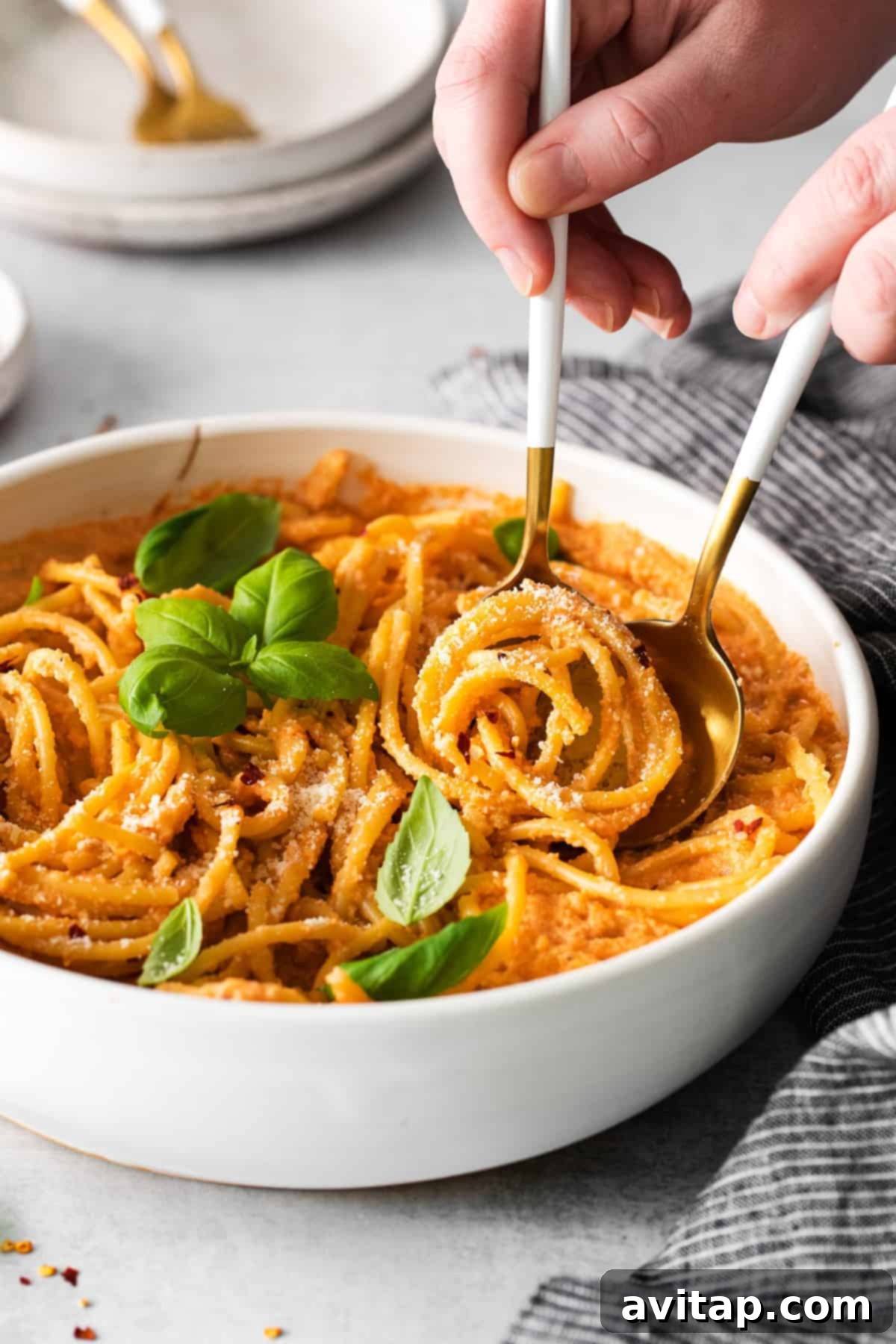 a bowl of creamy vegan pasta topped with fresh basil and red pepper flakes