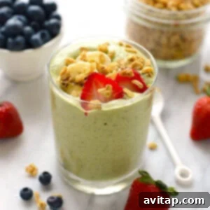 Delicious green smoothie in a glass with berries on top, ready to drink.