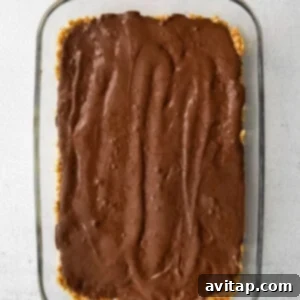 chocolate being poured and spread on the rice crispy bars.