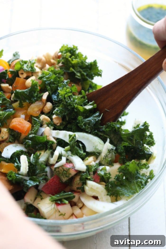If you are looking for a new salad recipe that is both delicious and nutritious, this massaged kale salad with fennel is perfect! Massaged kale is easy to eat, great for meal prep, and packed with flavor! Mixing the massaged kale salad in a bowl.