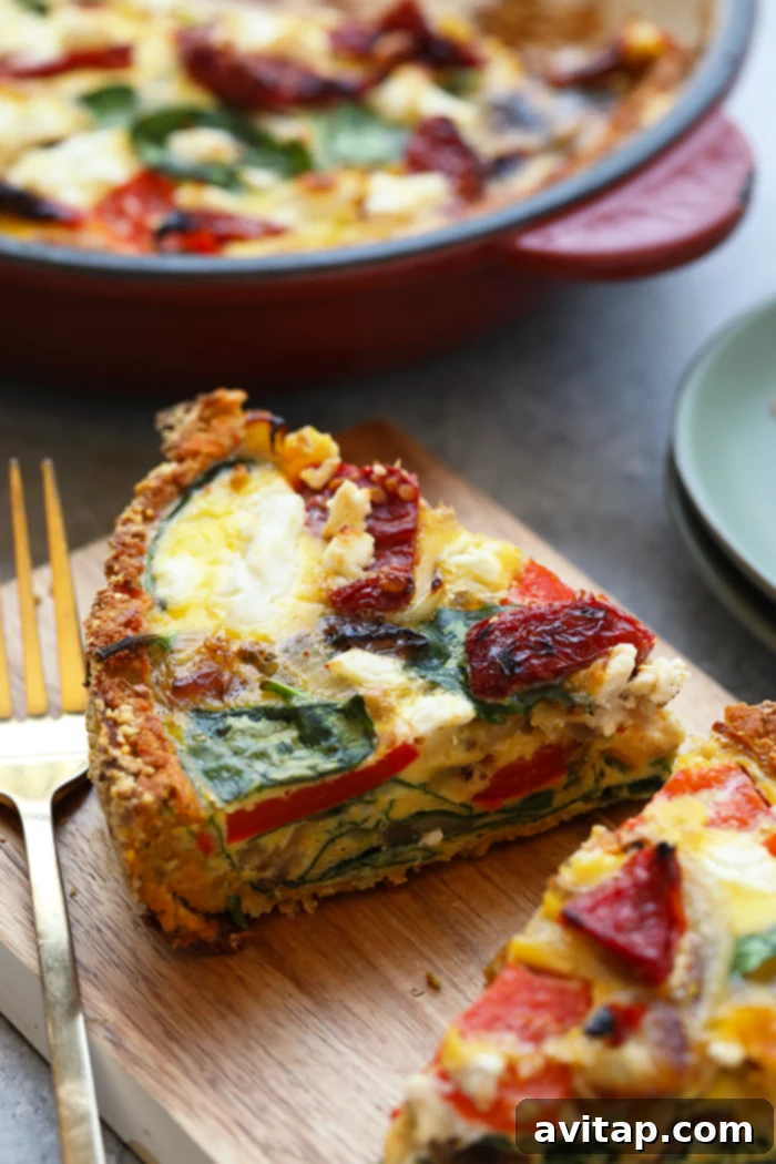 A perfectly baked slice of sweet potato crust quiche resting on a wooden cutting board, showcasing its golden crust and vibrant veggie filling.