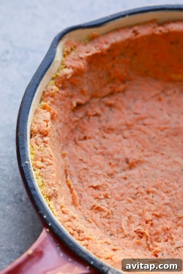 A golden-brown sweet potato crust, perfectly formed in a pie pan, ready for its delicious quiche filling.