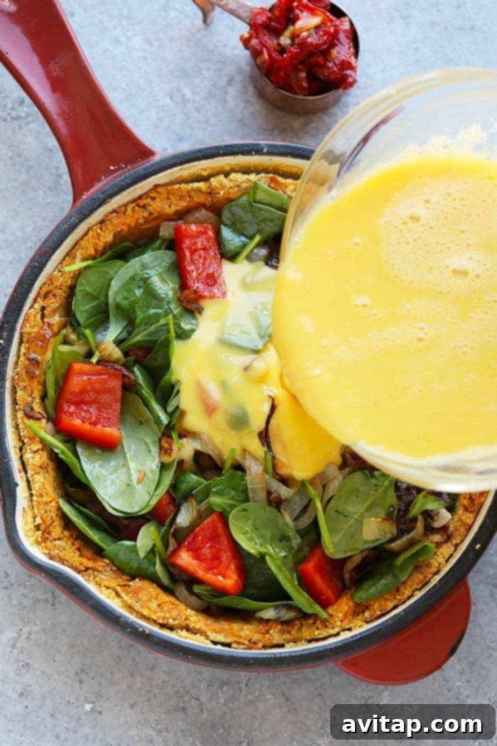 A vibrant mix of fresh spinach, red bell peppers, and caramelized onions sautéing in a pan, preparing for the quiche filling.