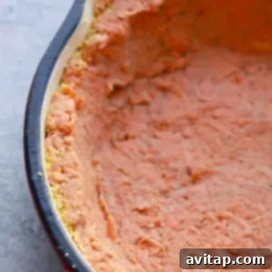 Close-up of a sweet potato crust quiche in a red baking dish with a partially visible black rim.