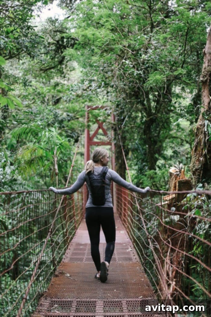 Woman standing on a suspension bridge overlooking the misty Monteverde Cloud Forest canopy