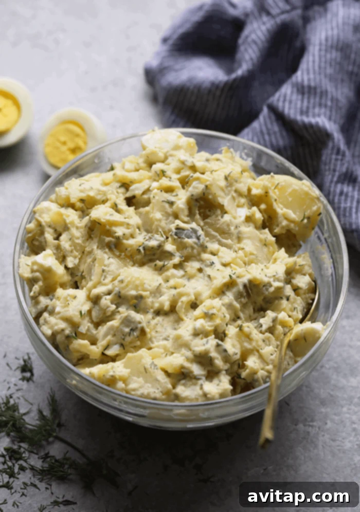 A serving of creamy Instant Pot Potato Salad in a rustic bowl, garnished with fresh dill.