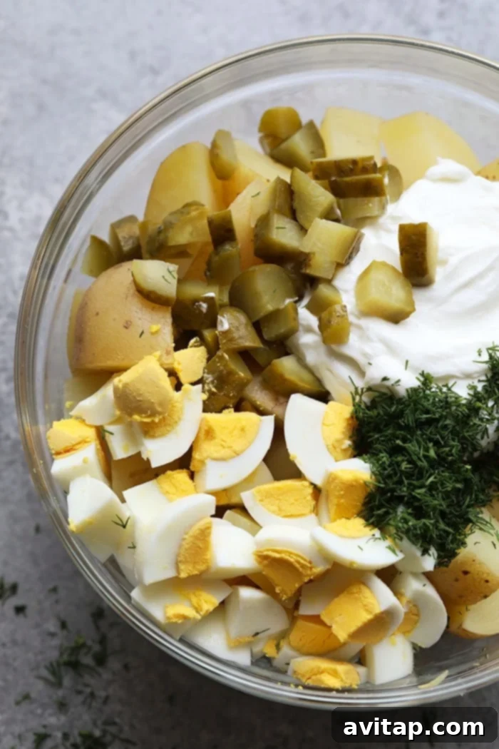 All the creamy Instant Pot potato salad ingredients, including tender potatoes, chopped eggs, and a vibrant dressing, combined in a large mixing bowl, ready to be chilled and served.