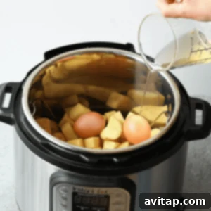 Pouring liquid mixture into the Instant Pot over potatoes and eggs.