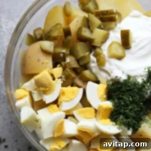 Ingredients for creamy potato salad mixed together in a bowl.