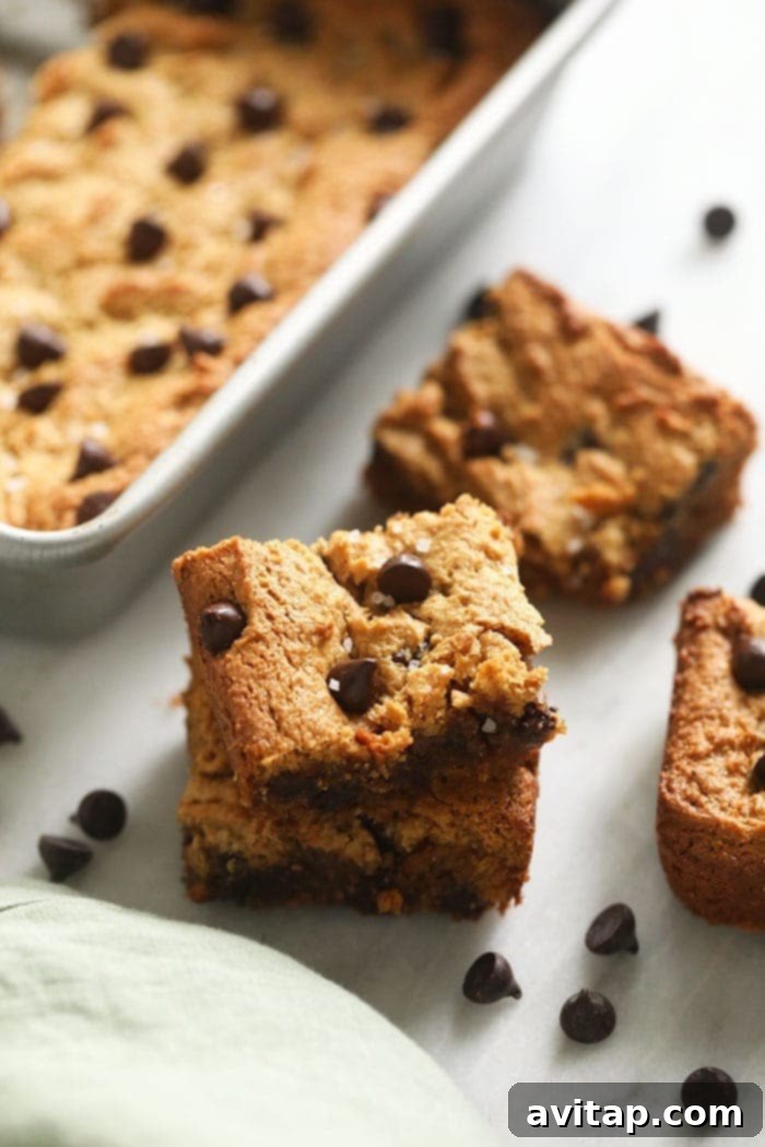 Two stacks of perfectly baked, gooey flourless blondies with visible chocolate chips