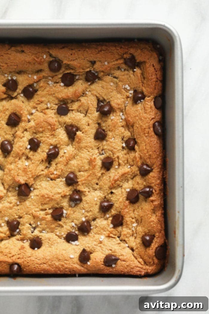 Beautifully baked flourless blondies cooling in a parchment-lined baking pan, ensuring easy removal.