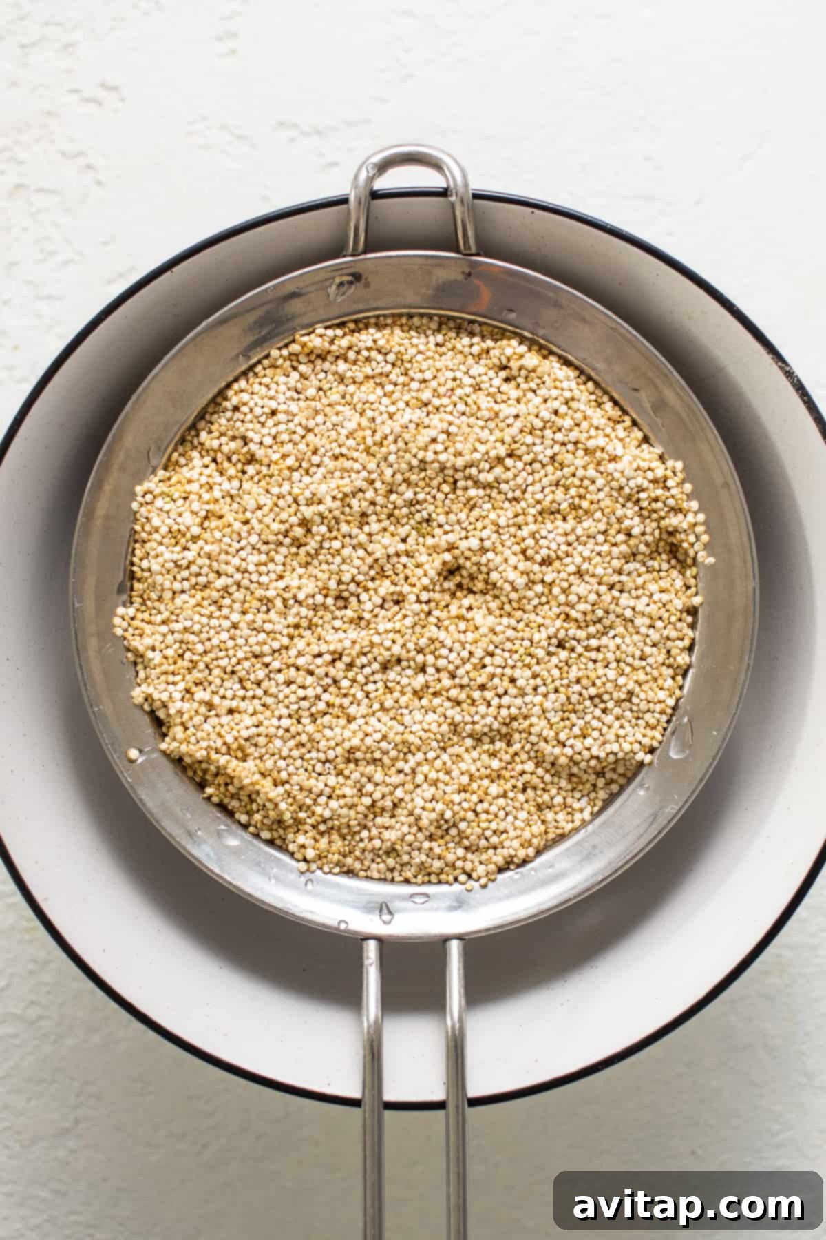 Effortless Instant Pot Quinoa 3 Uncooked quinoa in a fine mesh sieve, ready for rinsing.