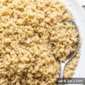A bowl of fluffy Instant Pot quinoa on a white plate with a spoon, ready to serve.