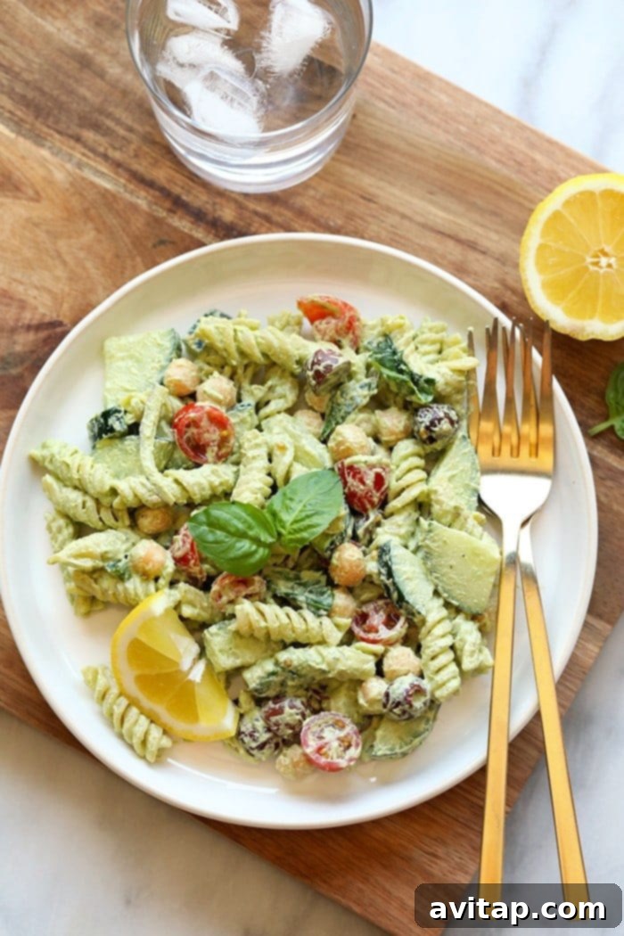 A delicious serving of creamy vegan pesto pasta salad, perfect for a healthy and satisfying meal. A close-up shot of creamy vegan pesto pasta salad served on a white plate, garnished with fresh basil, ready to be eaten.