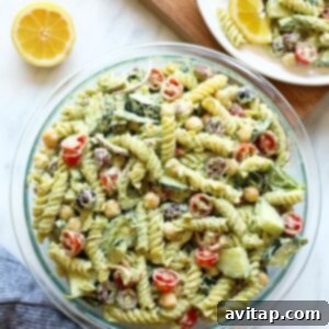 A close-up of Greek pasta salad with chickpeas, lemon, and a creamy pesto dressing, ready to be mixed.