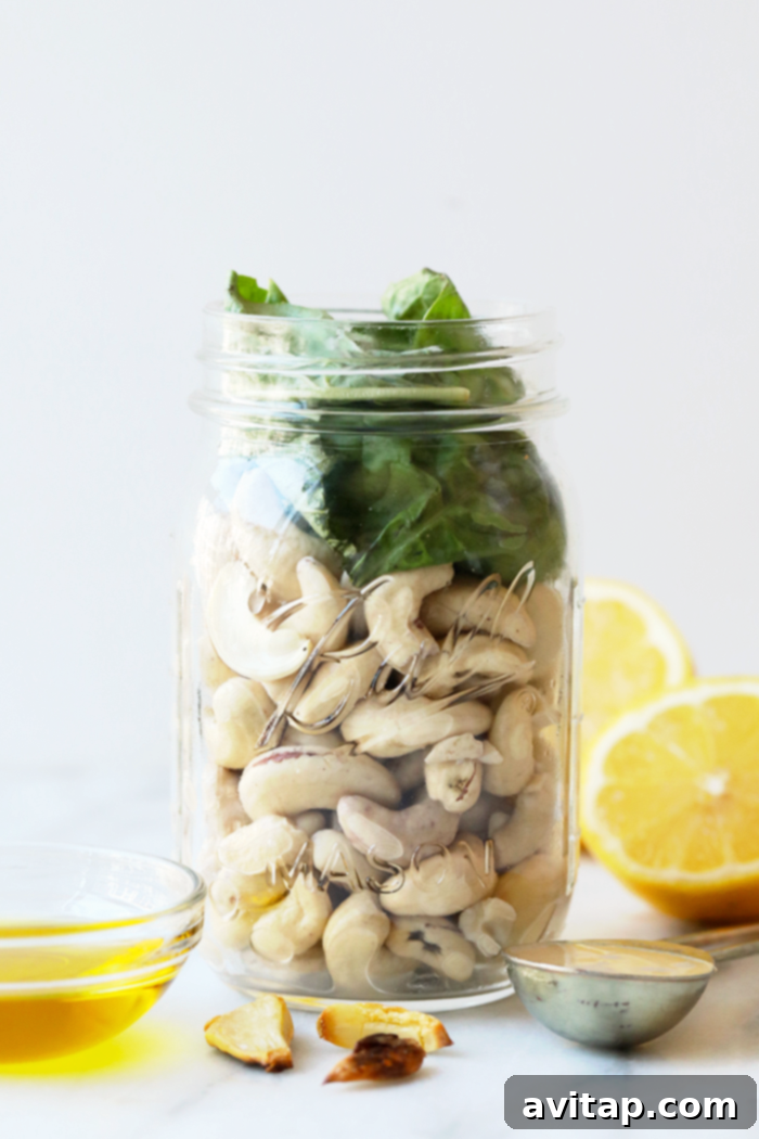 Perfect for meal prep: store your vegan pesto pasta in a jar for easy, delicious lunches throughout the week. A glass jar filled with vibrant green vegan pesto pasta, showing the rich sauce coating the noodles and vegetables, ready for storage.
