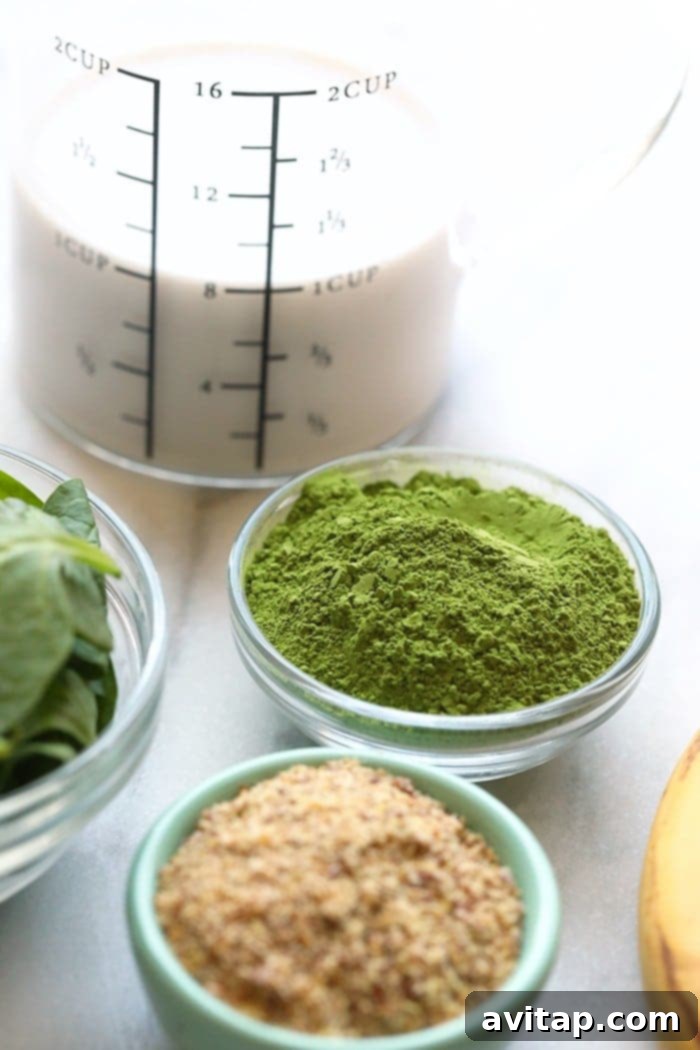 Gathering the healthy ingredients for your homemade Banana Matcha Smoothie: frozen bananas, vibrant matcha, fresh spinach, and creamy almond milk. A flat lay photograph showcasing all the fresh ingredients needed to make a banana matcha smoothie, including bananas, spinach, matcha powder, and almond milk.