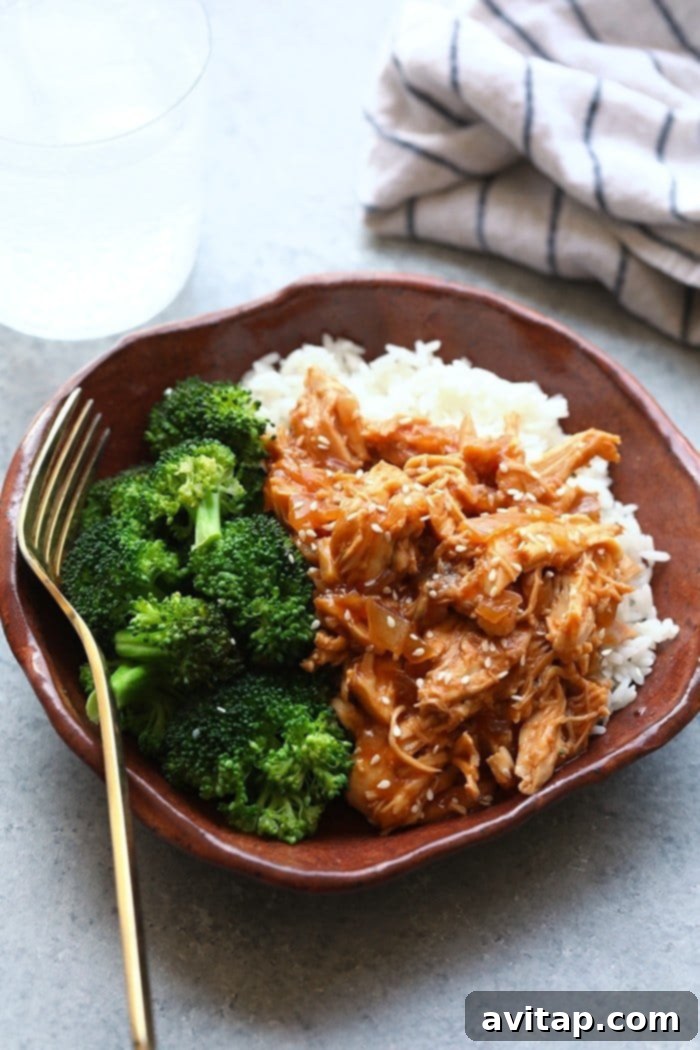 Delicious Crockpot Sesame Chicken in a bowl with fluffy white rice and vibrant steamed broccoli, garnished with sesame seeds.