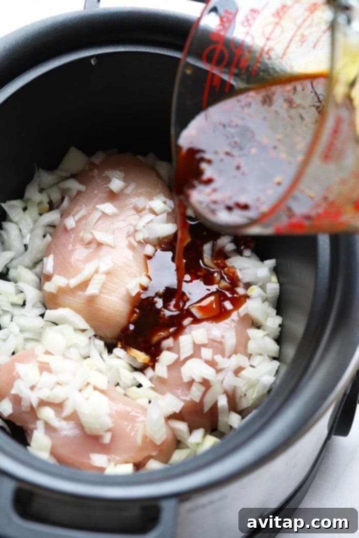 Succulent chicken breasts simmering in a rich, savory sesame sauce inside a slow cooker, promising a tender and flavorful meal.