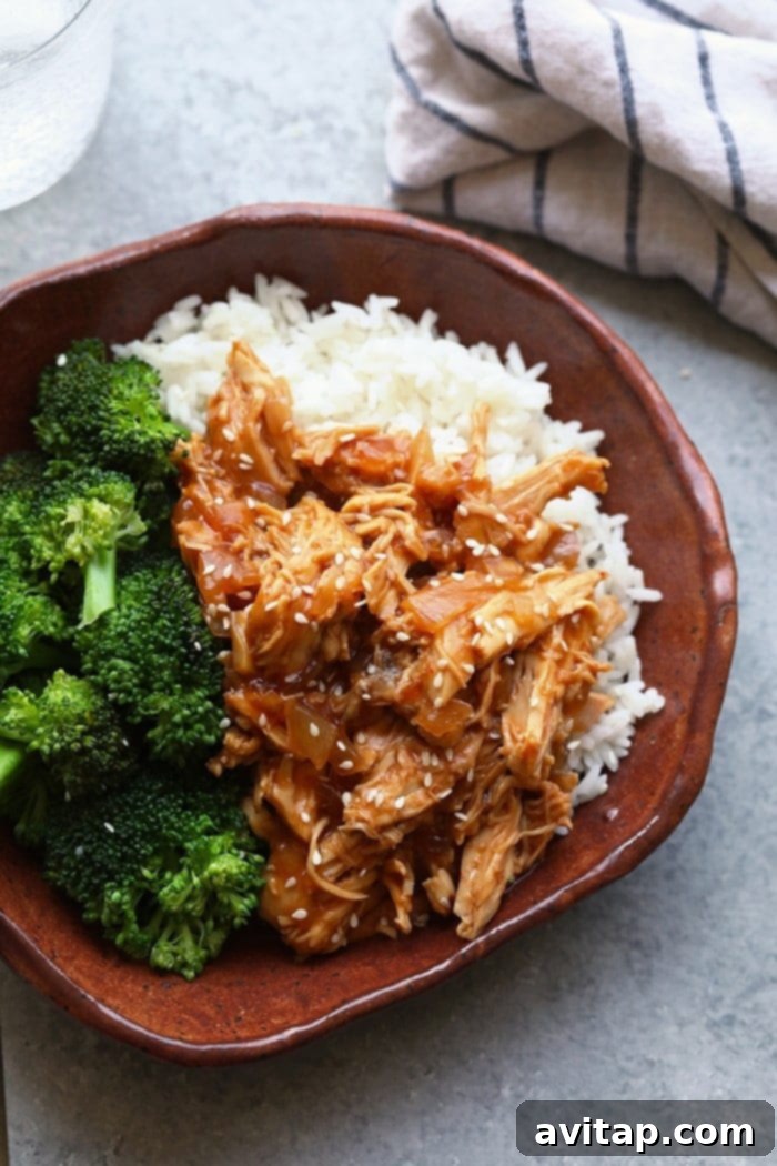 A beautifully presented bowl of Crockpot Sesame Chicken, garnished with sesame seeds and fresh green onions, ready to be enjoyed.
