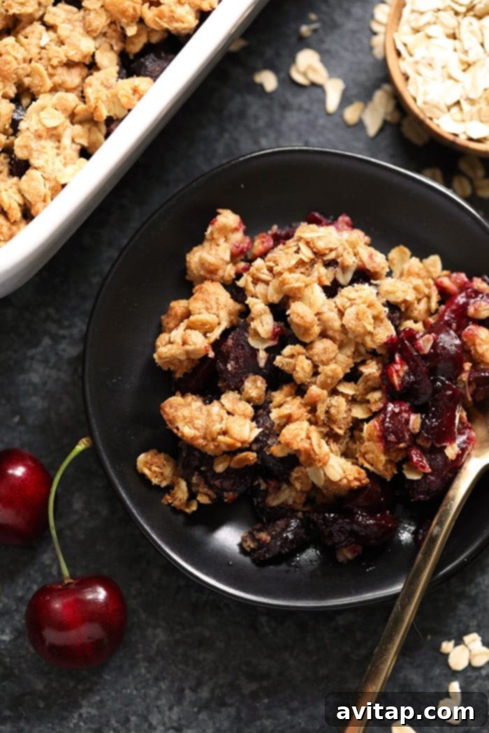 Cherry crisp in a bowl, ready to be served with a spoon