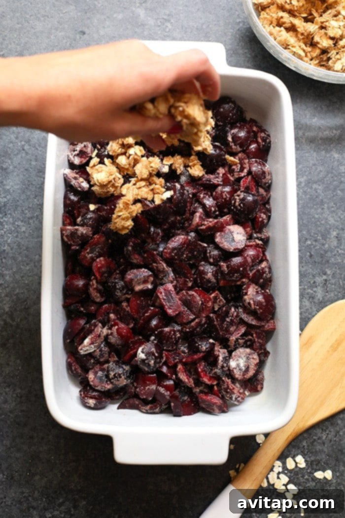 Baked cherry crisp in a rectangular casserole dish, cooling on a counter