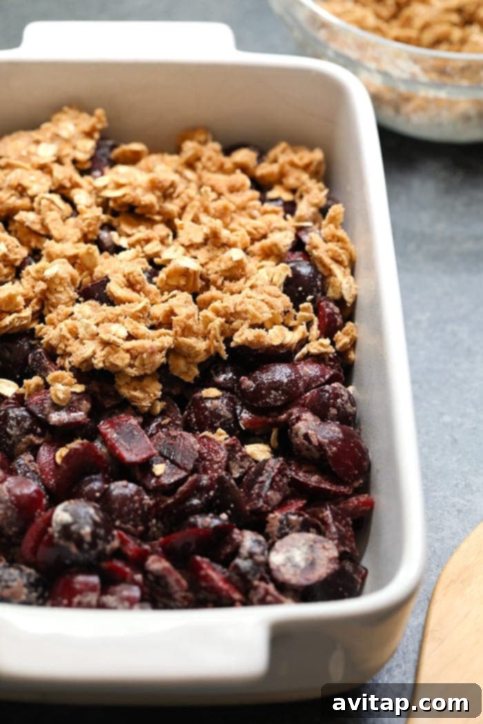 Close-up of baked cherry crisp in a casserole dish, showing the bubbly filling and golden brown oat topping