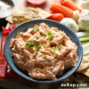 A slow cooker filled with creamy buffalo chicken dip, surrounded by fresh carrots, celery sticks, and crackers, creating an inviting spread for an easy and delicious appetizer.