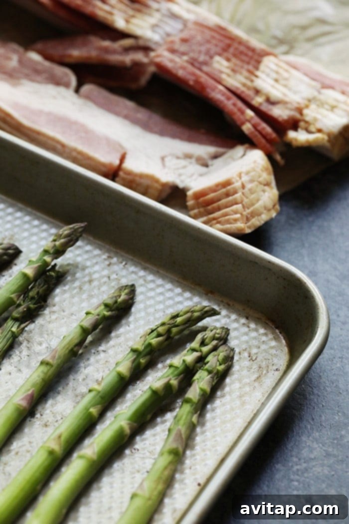 Fresh ingredients for making bacon wrapped asparagus: green asparagus and raw bacon strips.